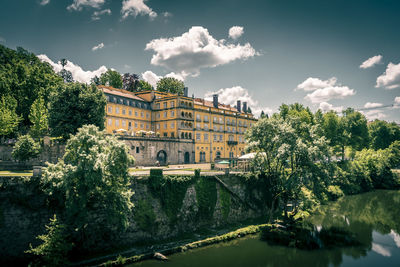 Arch bridge over river by buildings against sky