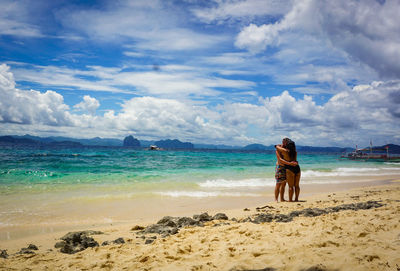 Rear view of man on beach against sky