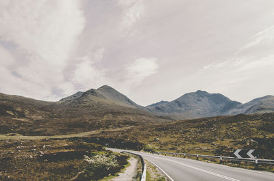 Road leading towards mountains against sky