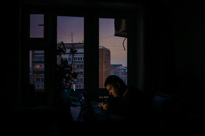 Side view of woman looking through window