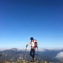 Female hiker standing on cliff against mountains