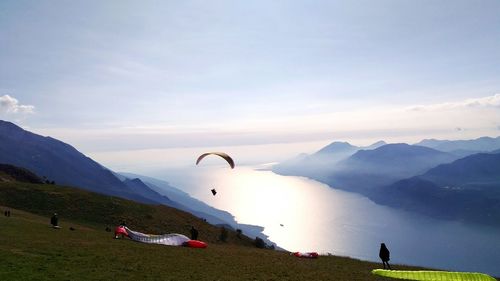 Scenic view of people paragliding on mountain against sky