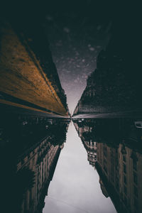 Reflection of buildings in puddle at night