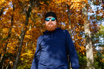 Portrait of bearded man in sunglasses standing against trees during autumn