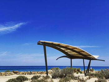 Lifeguard hut on beach against clear blue sky