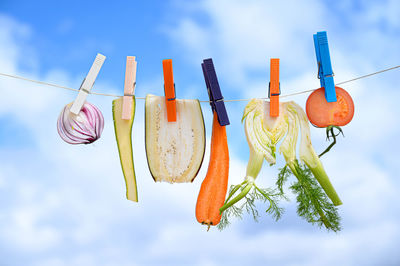 Low angle view of clothespins hanging against sky