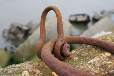 Close-up of rusty metallic mooring ring on rock