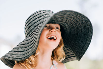 Portrait of a young girl smiling outside with a large sun hat on