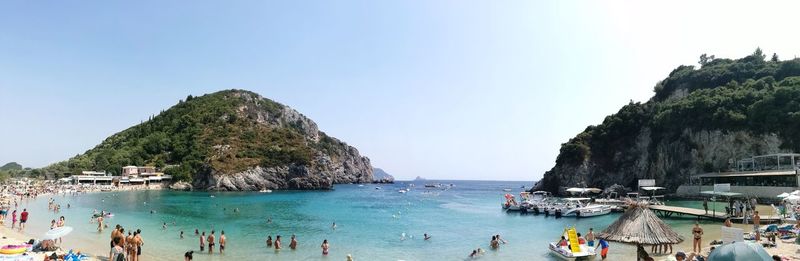 People swimming in sea against clear sky