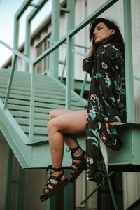 Young woman looking down while sitting on railing