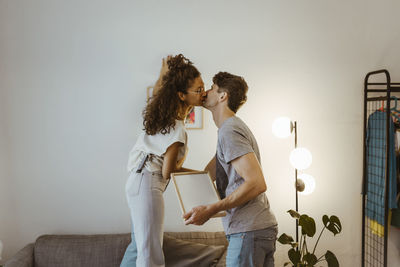 Side view of couple kissing each other against wall at home