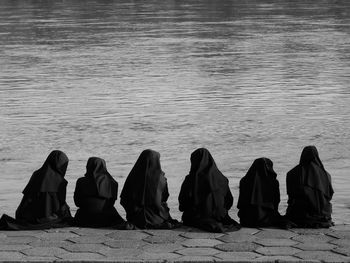 Rear view of women hijab praying at lakeshore