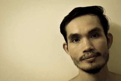 Close-up portrait of young man against beige background