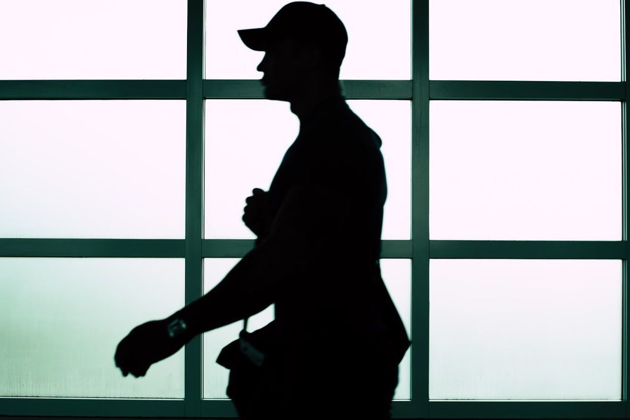 SILHOUETTE MAN STANDING AGAINST WINDOW
