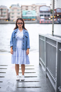 Portrait of woman standing against railing