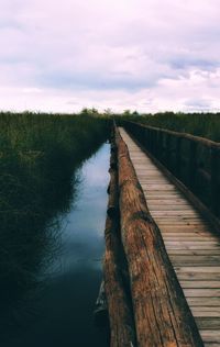 Wooden bridge over canal against sky