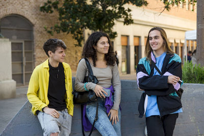 Friends talking while standing outdoors on the street.