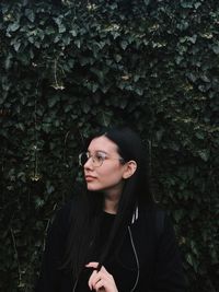 Portrait of beautiful young woman standing by plants in forest