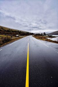 Empty road against cloudy sky