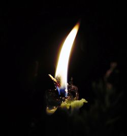 Close-up of burning candle against black background