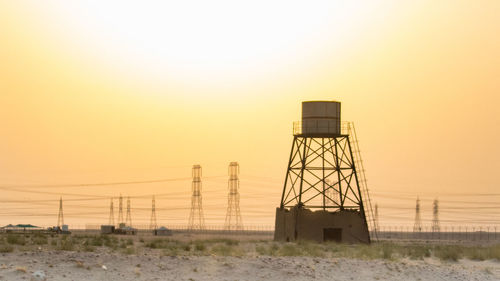 Water tower on landscape against sky during sunset