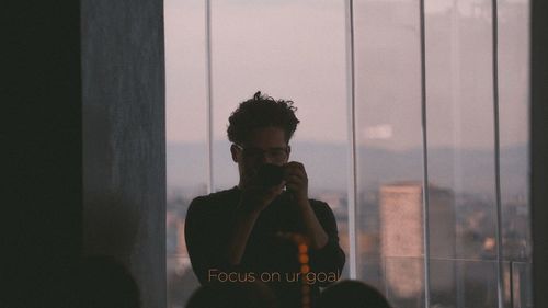 Portrait of man photographing through window
