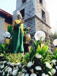 Low angle view of saint statue by flowers outside church