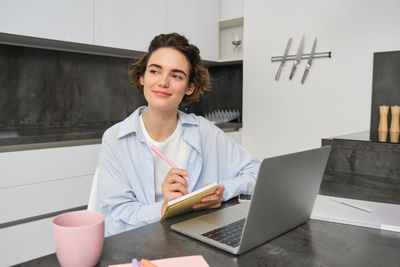 Portrait of young businesswoman using laptop while sitting on table