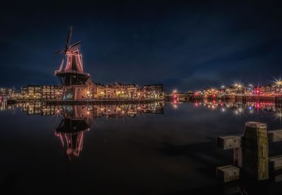 Illuminated bridge over river against sky at night