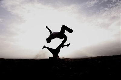 Silhouette of woman jumping on landscape