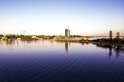 Scenic view of lake by buildings against sky at sunset