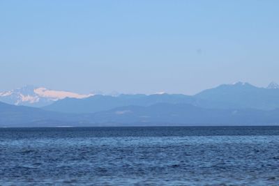 Scenic view of sea and mountains against clear sky