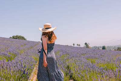Rear view of woman standing on field against clear sky