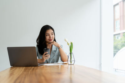 Young woman using mobile phone while sitting at home