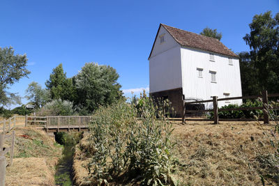 Built structure on field by building against clear blue sky