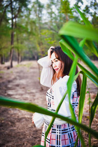 Woman holding umbrella standing against plants