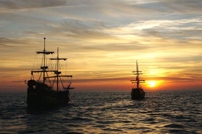 Sailboats in sea against sky during sunset