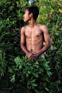 Young man standing by plants on land