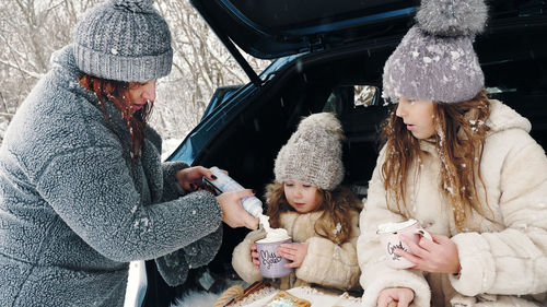 Winter tea picnic. happy family is having tasty snack, a tea party with cream, outdoors. 