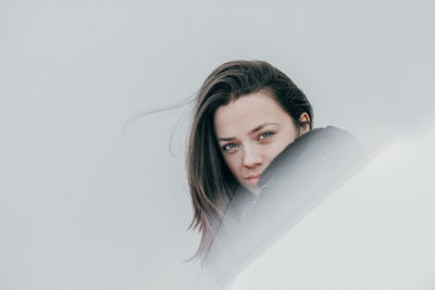 Portrait of young woman against white background