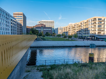 Buildings by river against sky