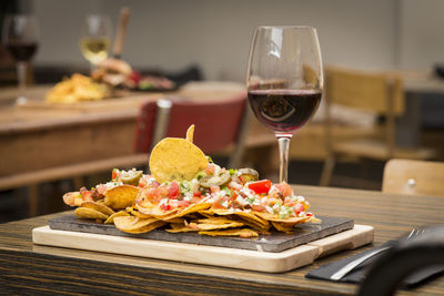 Nachos by red wine in glass served on wooden table