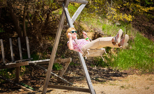 Senior woman joyfully swinging on a swing and having fan