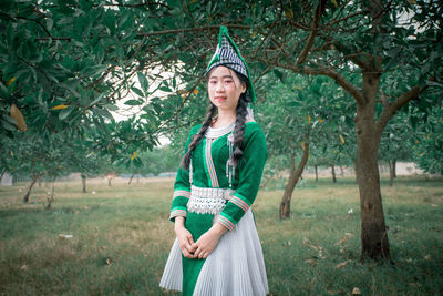 Portrait of smiling young woman standing against trees