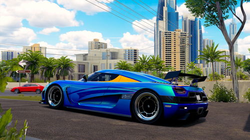 Cars on road by buildings against blue sky