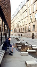 Man sitting on street amidst buildings in city