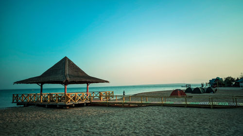 Lifeguard hut on beach against clear sky during sunset