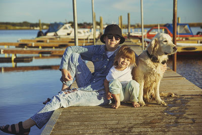 Children with their dog sit on a pier in denmark