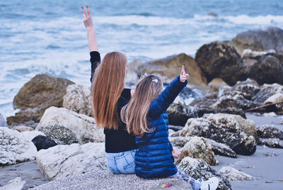 Rear view of women standing on rock at beach