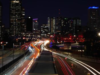 High angle view of light trails on road amidst buildings at night
